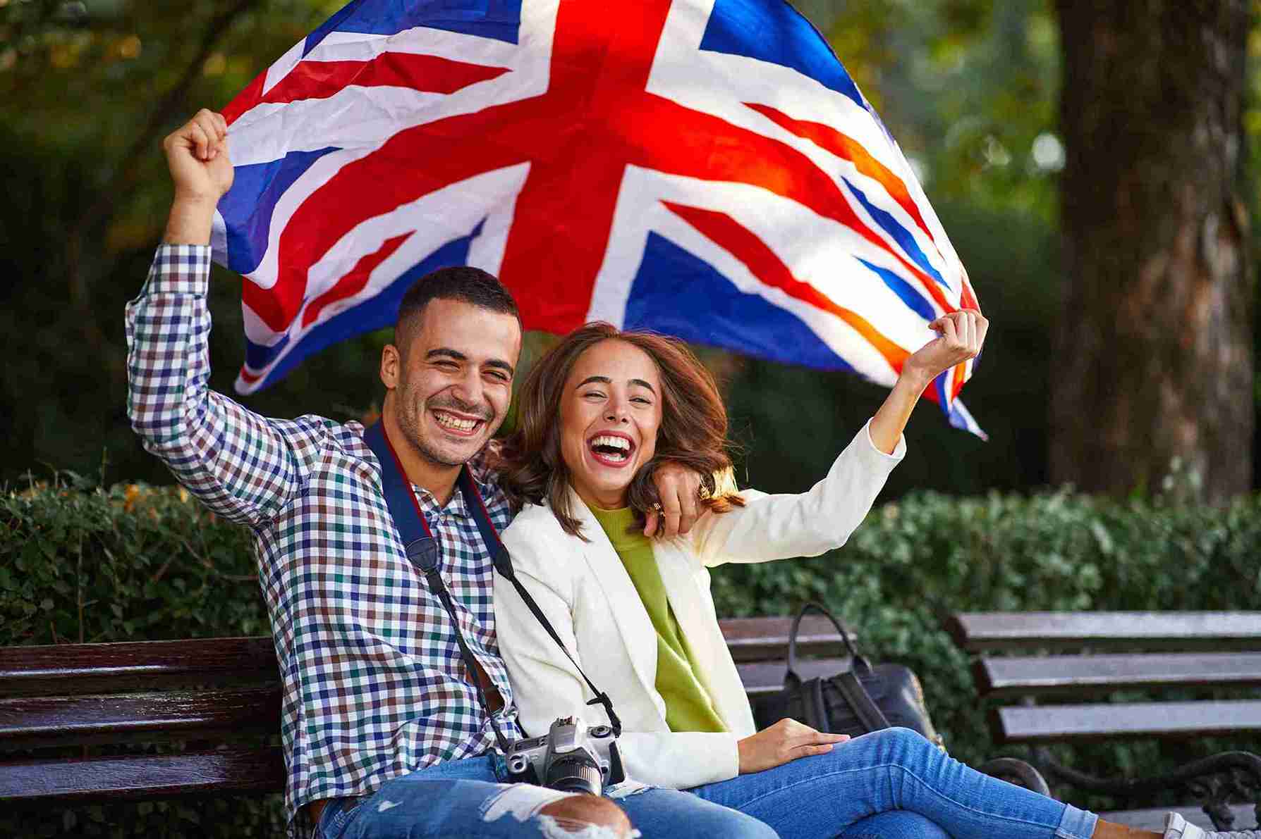 cheerful-couple-holding-british-flag-in-an-urban