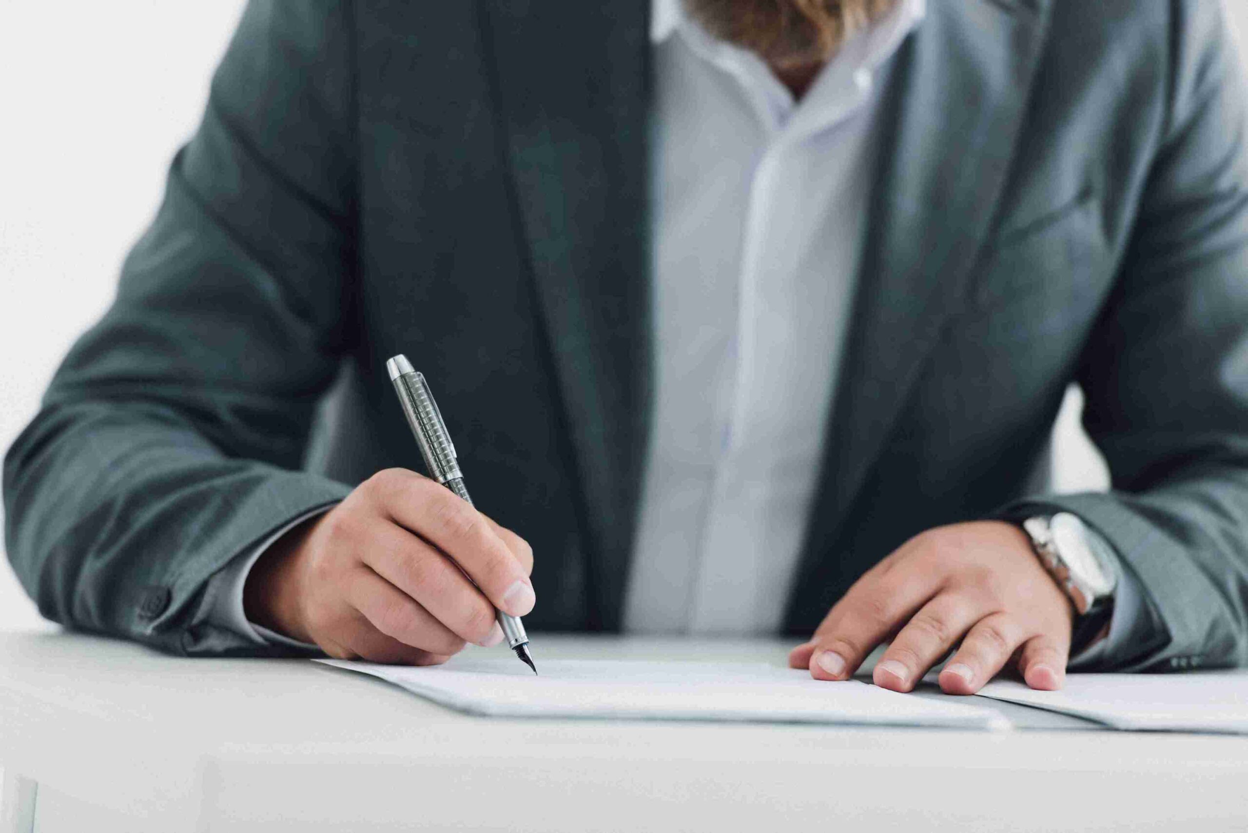man-in-suit-signing-documents-at-office-desk