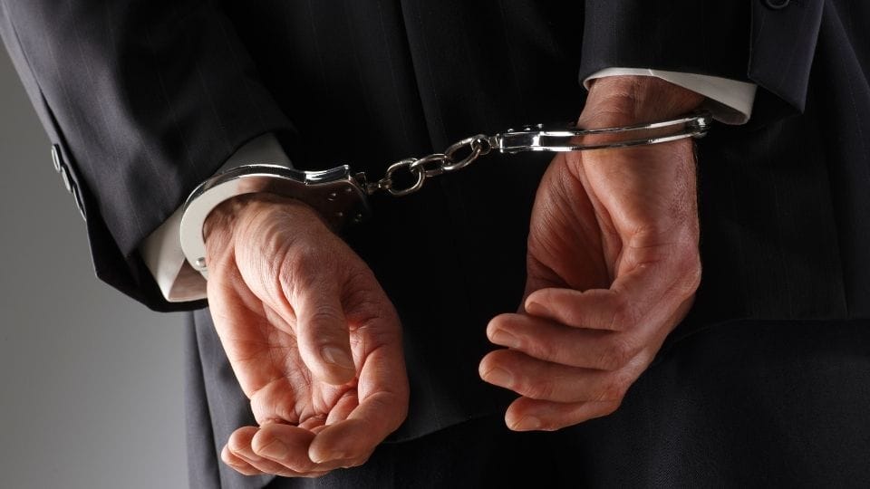 UK White Collar Crime Cases (in the image a man guilty of a white collar crime case can be seen with handcuffs)