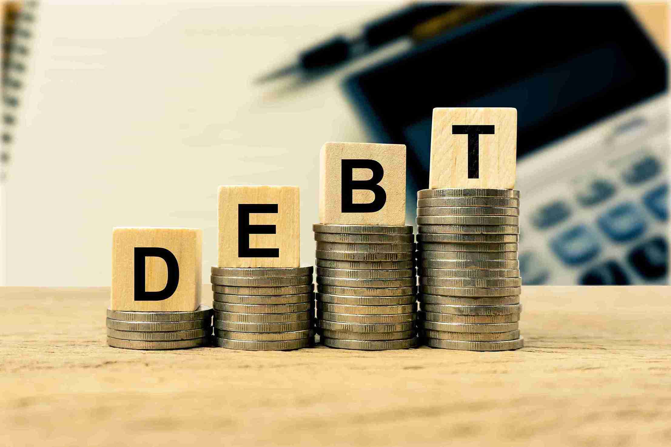 debt-concept-with-wooden-blocks-and-stacked-coins