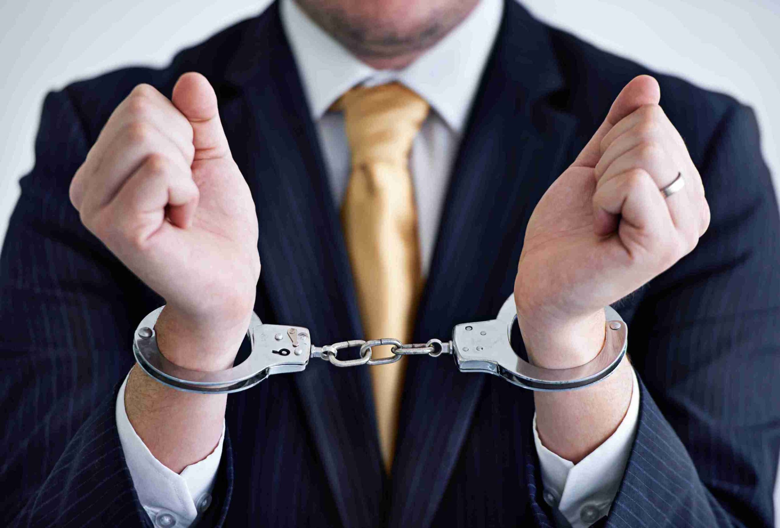 UK White Collar Crime Cases (in the image a man guilty of a white collar crime case can be seen with handcuffs)