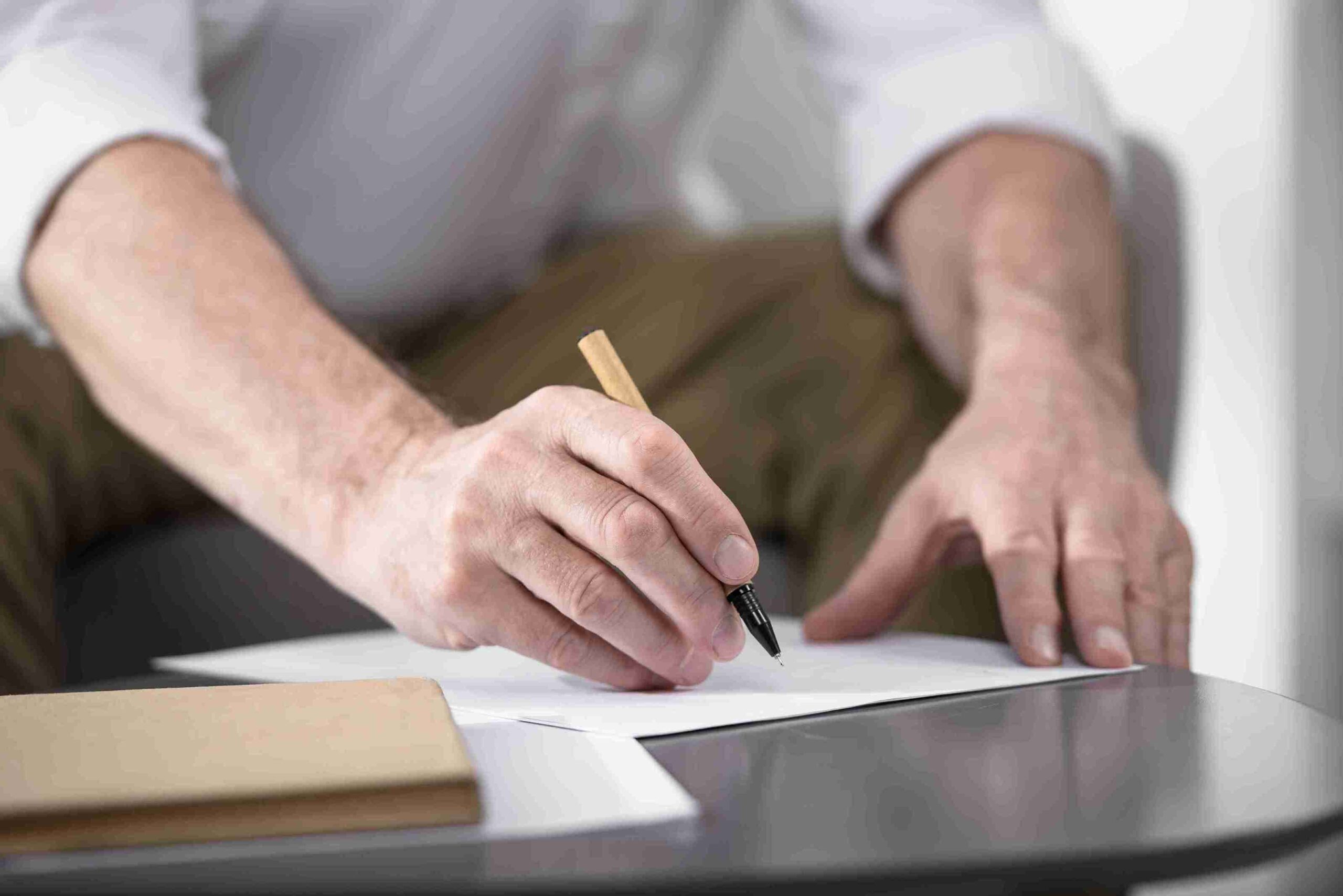 man-writing-with-pen-on-paper-at-table
