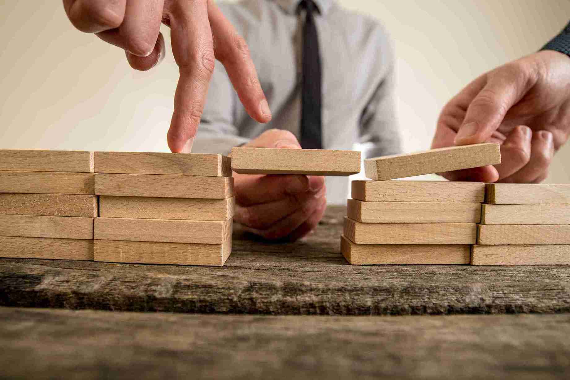 businessmen-building-a-wooden-block-bridge-togethe