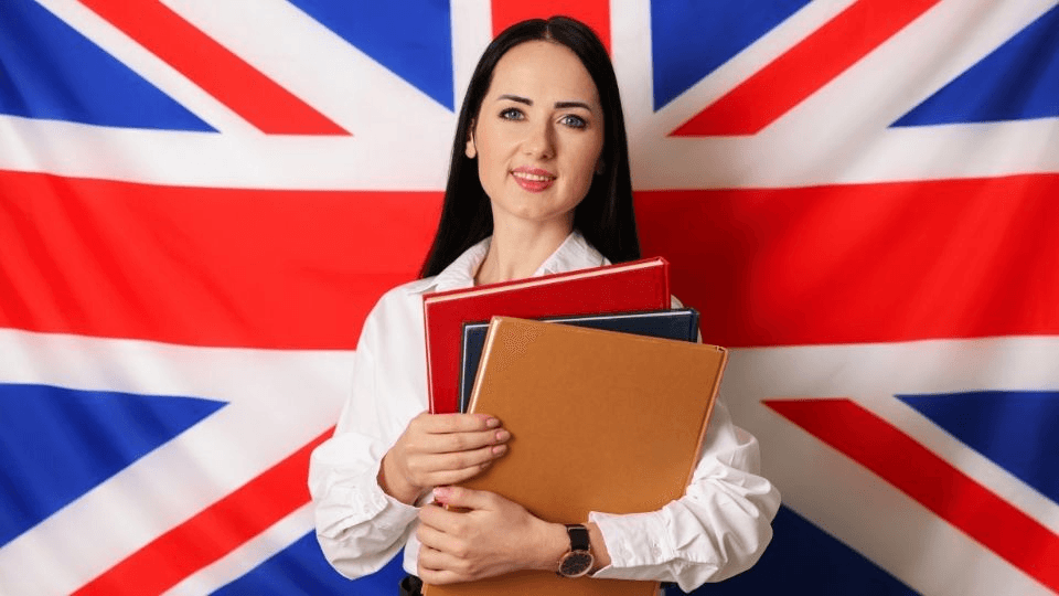 (In the image a woman can be seen holding books in front of UK flag to indicate knowledge of english and preparing for life in the uk test)
Naturalisation requirements