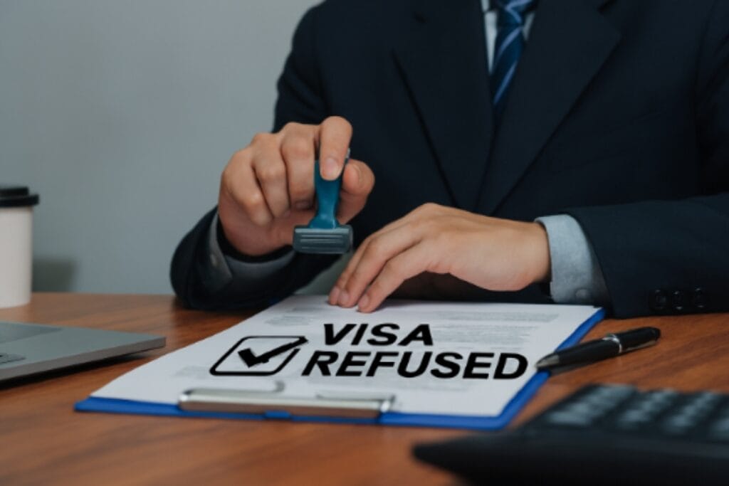 Document displaying a prominent "Visa Refused" stamp, signifying denial of visa application.