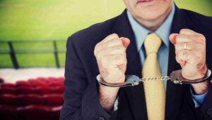 A man holds handcuffs in front of another person, suggesting a tense or confrontational situation.