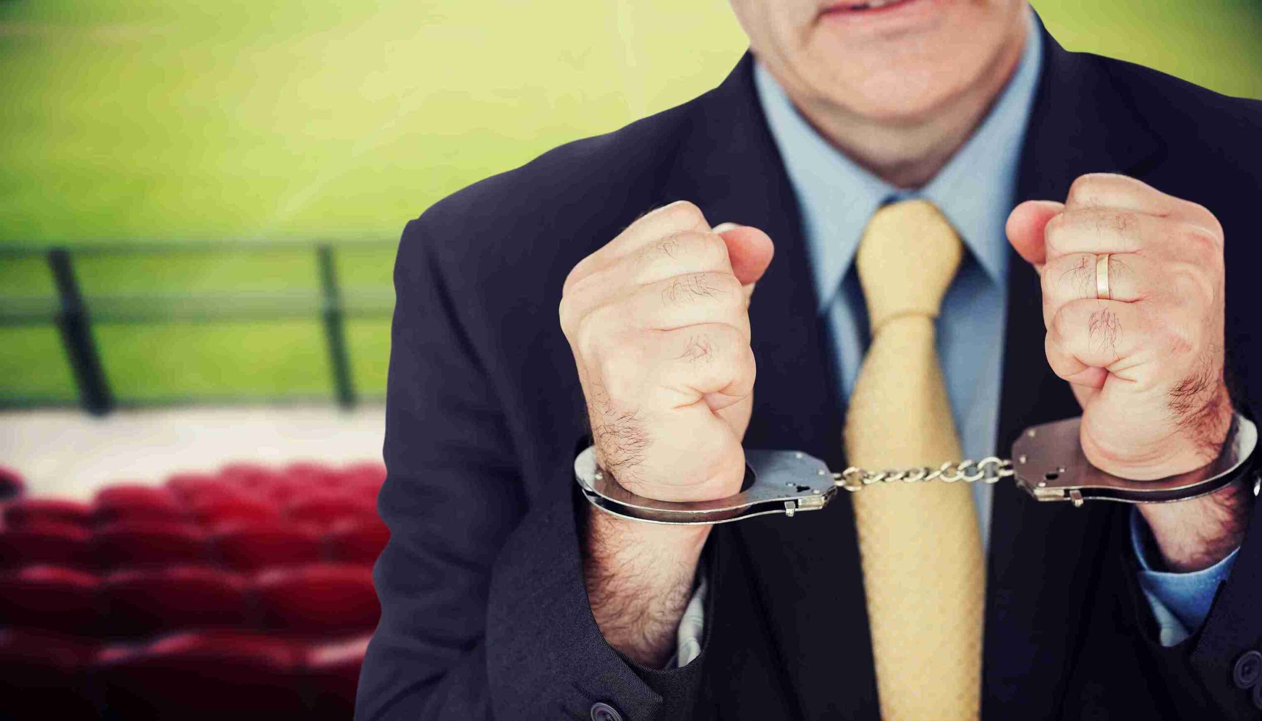 A man holds handcuffs in front of another person, suggesting a tense or confrontational situation.