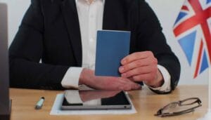 Business professional holding a passport with UK flag in the background, symbolizing visa application or review