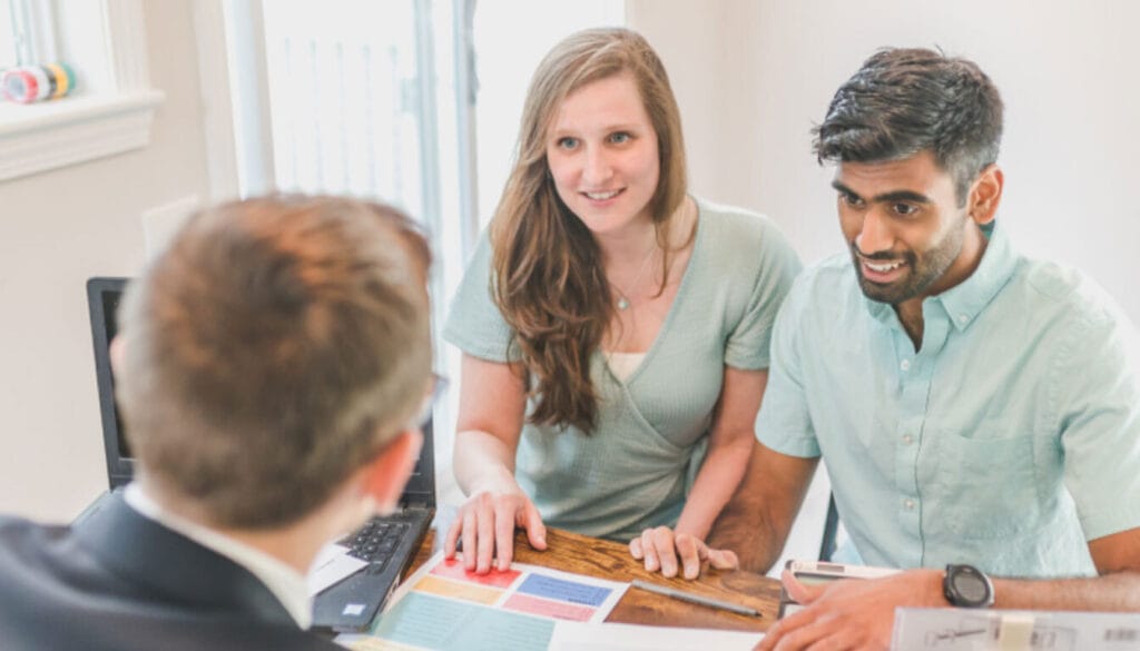 A young couple at a desk discussing the UK spouse visa document checklist and financial requirements with a consultant to ensure a smooth application process.