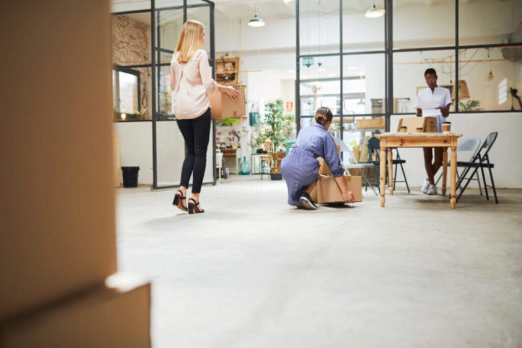 (Employees carrying boxes in a new office space during the execution phase of a business relocating to the UK.) business relocation UK