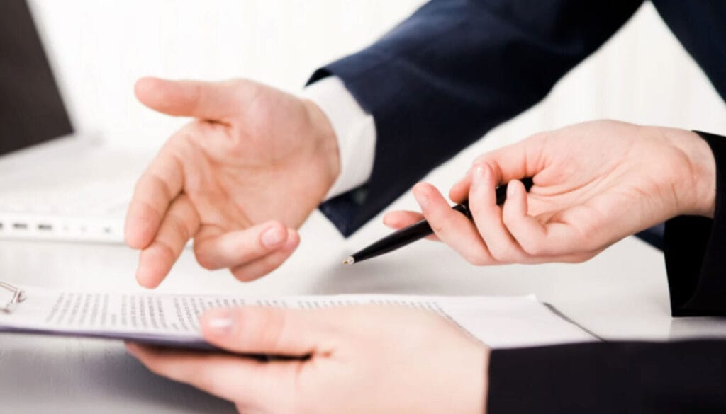 Close-up of two people pointing to and signing visa documentation or Certificate of Sponsorship (CoS).