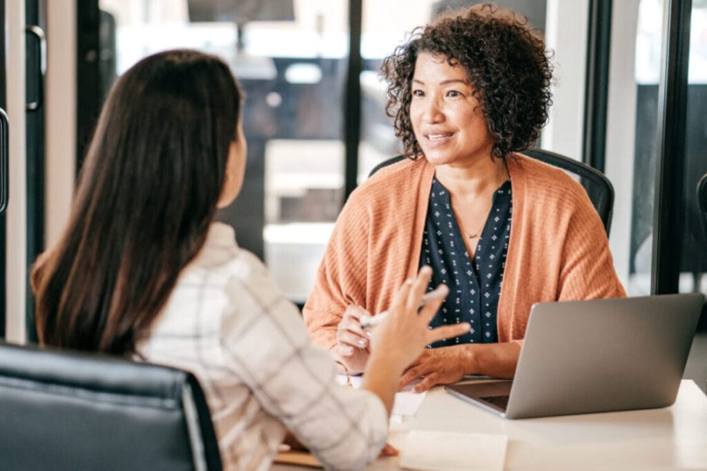 (Two professional women discussing corporate relocation UK compliance and employee rights during a business meeting.)
