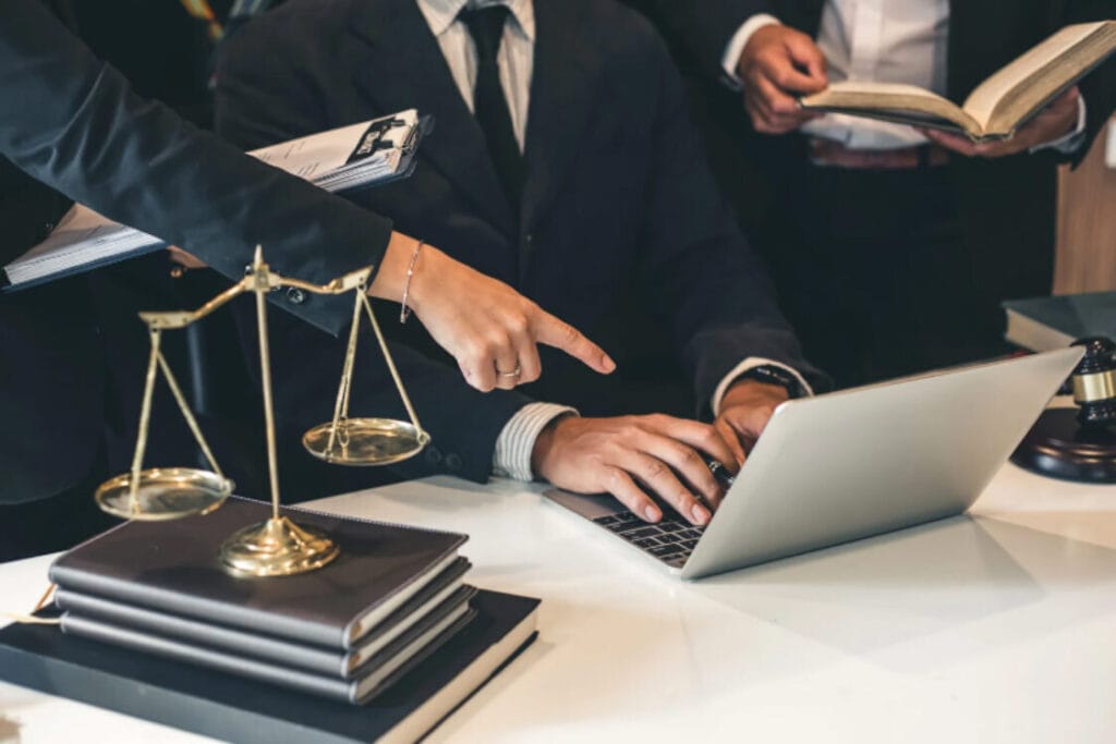 (Close-up of scales of justice next to a lawyer checking criminal records on a laptop for immigration purposes.)