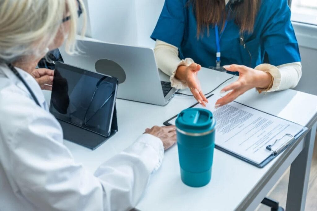 (Two healthcare workers reviewing documents and a digital tablet, highlighting the administrative and planning requirements for UK visa compliance.)Immigration Challenges