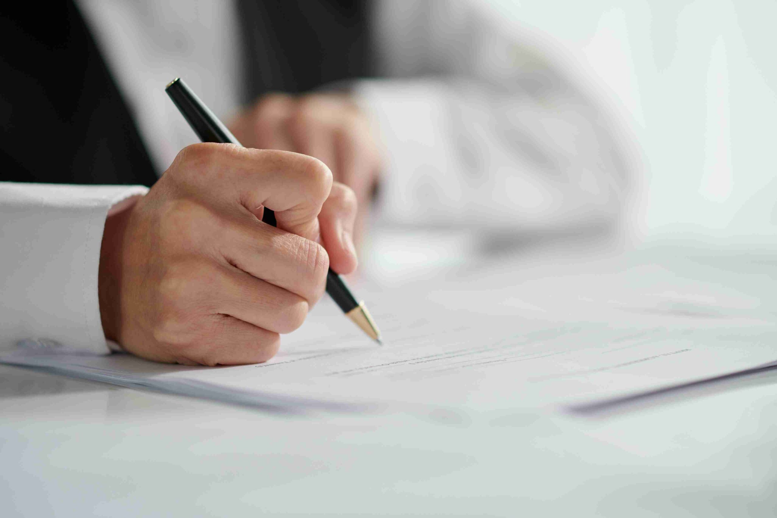 Adult signing document with pen at work.
