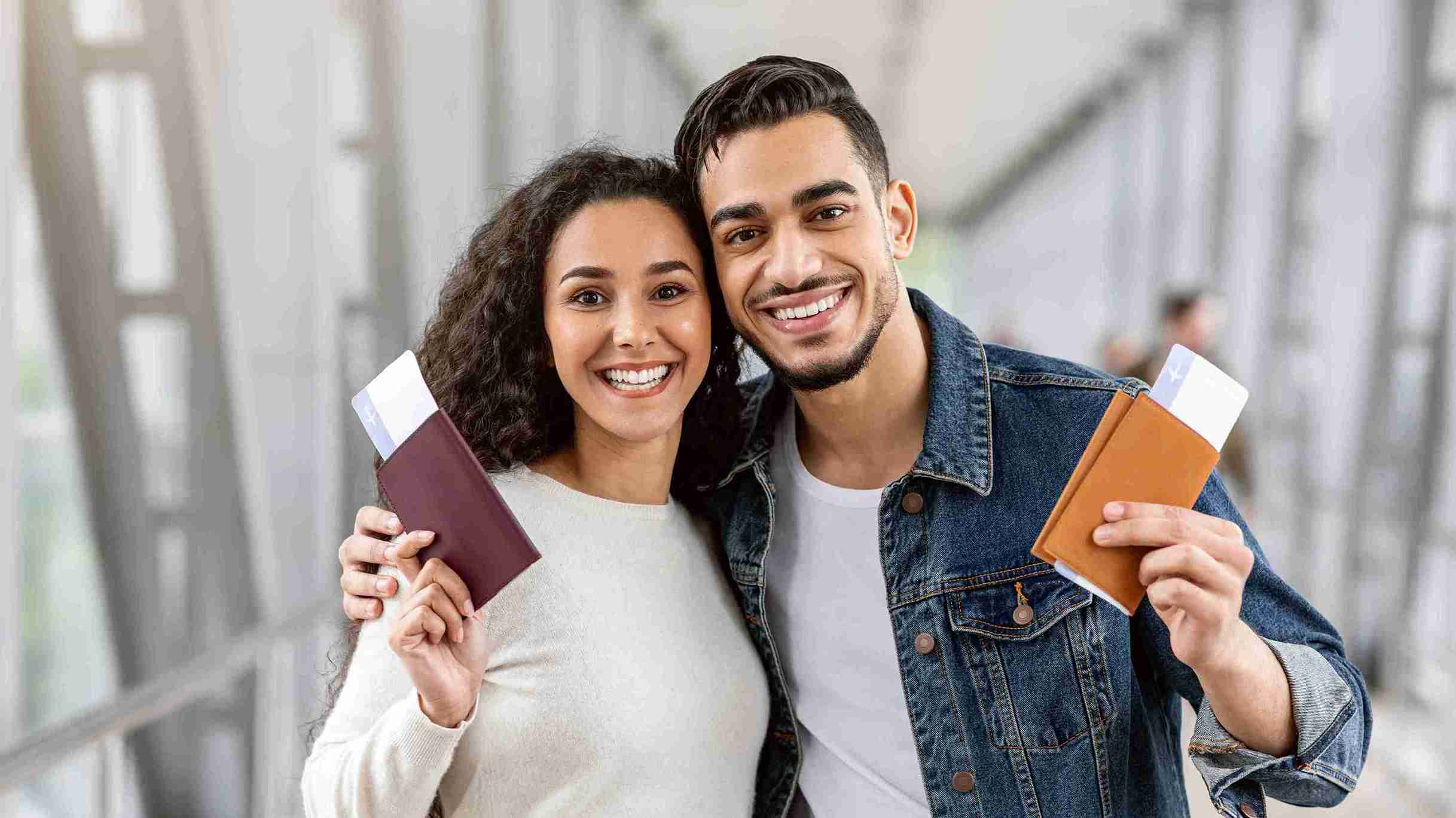 A man and woman proudly hold up their passports, smiling and ready for their next adventure together.